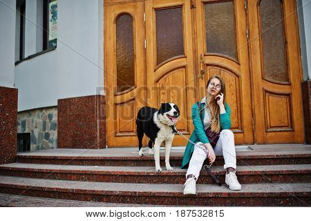 Trendy Girl At Glasses And Ripped Jeans With Russo-european Laika (husky) Dog On A Leash, Against Wo