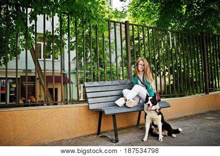 Trendy Girl At Glasses And Ripped Jeans With Russo-european Laika (husky) Dog On A Leash, Against Be