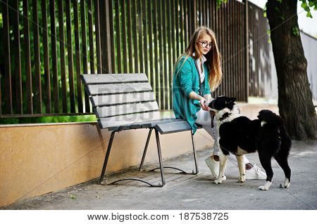 Trendy Girl At Glasses And Ripped Jeans With Russo-european Laika (husky) Dog On A Leash, Against Be