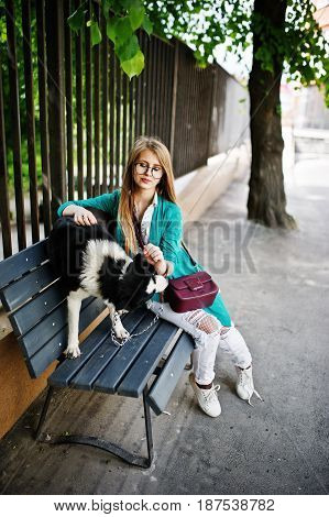 Trendy Girl At Glasses And Ripped Jeans With Russo-european Laika (husky) Dog On A Leash, Against Be