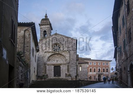 SAN QUIRICO D'ORCIA,ITALY-APRIL 24,2016::people stroll near the church in the San Quirico town square during a cloudy day.