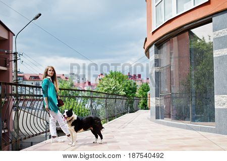 Trendy Girl At Glasses And Ripped Jeans With Russo-european Laika (husky) Dog On A Leash, Against Bu