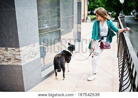 Trendy Girl At Glasses And Ripped Jeans With Russo-european Laika (husky) Dog On A Leash, Against Bu