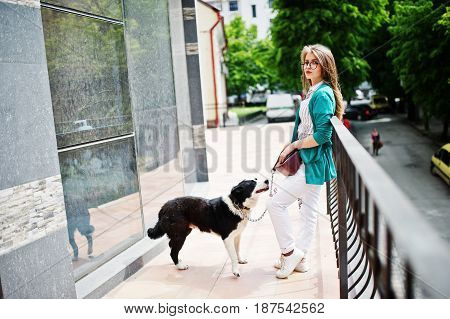 Trendy Girl At Glasses And Ripped Jeans With Russo-european Laika (husky) Dog On A Leash, Against Bu