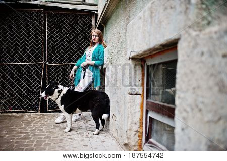 Trendy Girl At Glasses And Ripped Jeans With Russo-european Laika (husky) Dog On A Leash, Against St