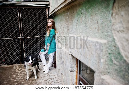 Trendy Girl At Glasses And Ripped Jeans With Russo-european Laika (husky) Dog On A Leash, Against St