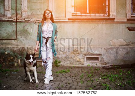 Trendy Girl At Glasses And Ripped Jeans With Russo-european Laika (husky) Dog On A Leash, Against St