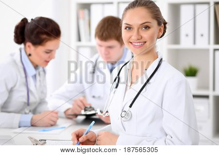 Happy doctor woman  with medical staff at the hospital sitting at the table and discussing medical history