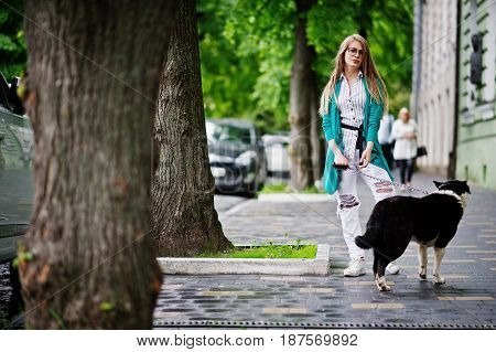 Trendy Girl At Glasses And Ripped Jeans With Russo-european Laika (husky) Dog On A Leash, Against St