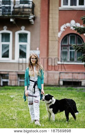 Trendy Girl At Glasses And Ripped Jeans With Russo-european Laika (husky) Dog On A Leash, Against St