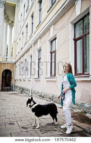 Trendy Girl At Glasses And Ripped Jeans With Russo-european Laika (husky) Dog On A Leash, Against St