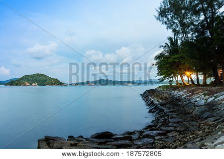 Stone path with lights leading into the sea. Cloudy sky and some small islands are also visible. Perfect vacation spot