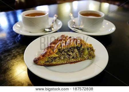 a piece of cake on a saucer and two cups of tea in a cozy cafe