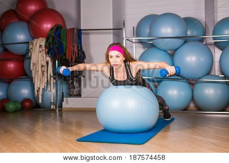 Woman exercising with dumbbells on a fitness ball.