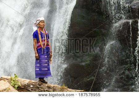 MAE KLANG LUANG, THAILAND - FEBRUARY 18, 2017 : A karen tribe woman in traditional dress is standing near the Pha Dok Seaw waterfall near the Mae Klang Luang village, Thailand