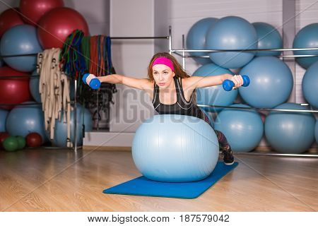 Woman exercising with dumbbells on a fitness ball.