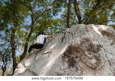 Young asian girl climbing rock boulder barehanded.