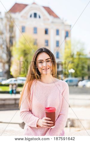 Woman At Fountain With Phone And Coffee To Takeaway On City Street