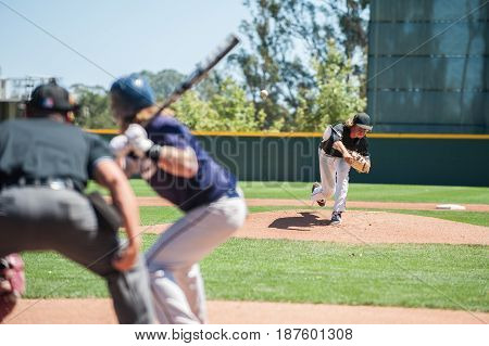 Baseball pitcher following through to pitch to left handed batter.