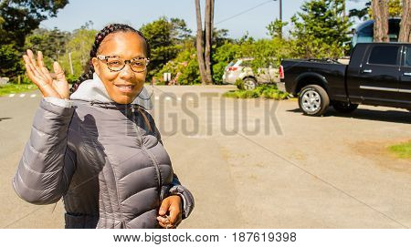 Pretty black woman waving at you smiling