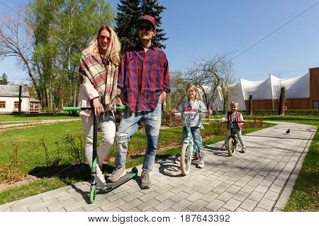 Young couple with children on scooters in park during day