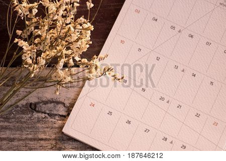Top View And Warm Tone. White Bouquet Flower Putting Beside Calendar Page On Wooden Are Background.