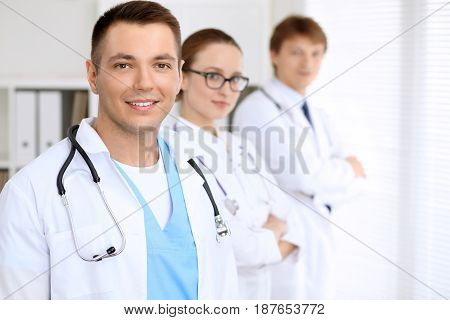 Cheerful smiling male doctor with medical staff at the hospital.