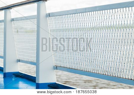 Detail view of metal grid on shipt banister with blurred sea on background