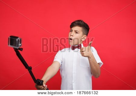 Young teen vlogger showing thumb up gesture while filming a video.