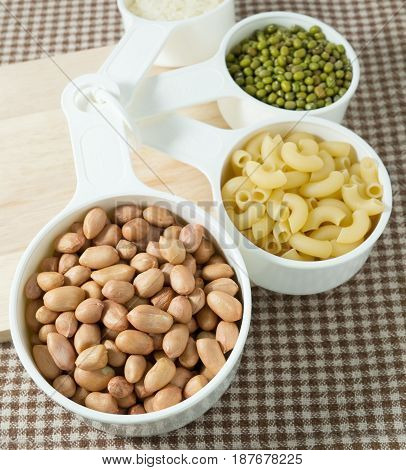 Foods High in Carbohydrate Raw Pasta Rice Peanuts and Mung Beans in Plastic Measuring Spoons.