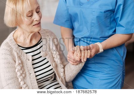 Regular checkup. Elderly frail cute woman sitting on a sofa at home and undergoing a general examination while experiencing some health issues