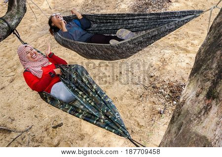 Labuan,Malaysia-Feb 19,2017:Young people relaxing & enjoying the hammock on tropical beach in Papan island,Labuan,Malaysia.