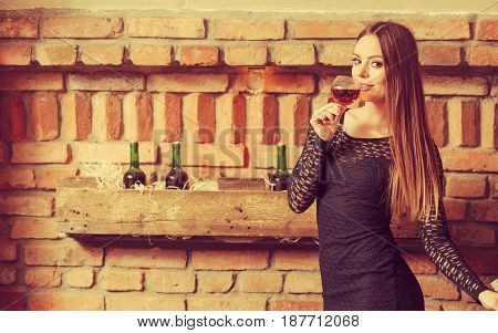 Woman Tasting Wine In Rural Cottage Interior