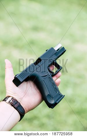 The gun is in his hand. The man is ready to shoot at the target
