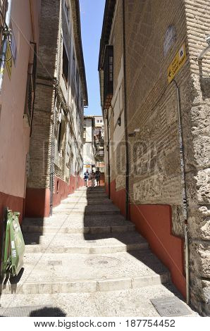 GRANADA, SPAIN - MAY 20, 2017: People descending by a narrow street in in the quarter of Albayzin that leads to the Darro way in Granada Andalusia Spain.