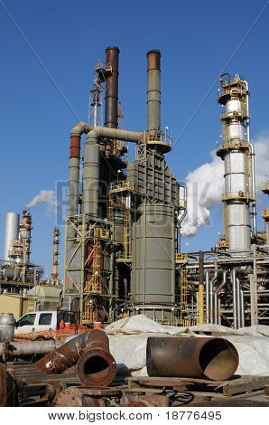 Paslı boruları ve diğer Endüstri/sanayii donatımı ön planda, arka planda Petrokimya tesisi