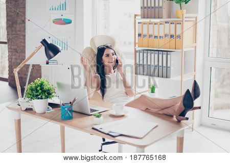 Young Lady Is Resting At Her Work Place By Talking To A Friend On Phone, Putting Her Feet On The Des