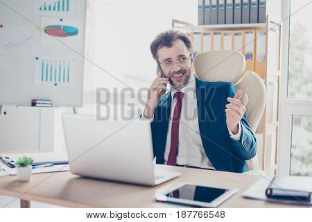 Cheerful Businessman Is Having A Phone Conversation At Work. He Is Smiling And Pointing With His Fin