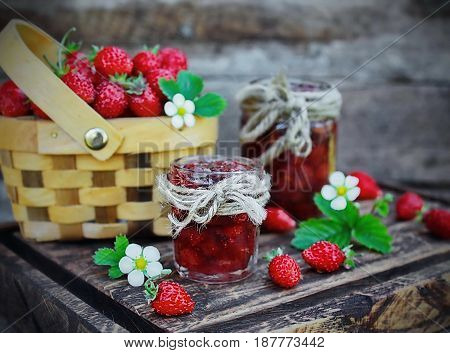 jam from wild strawberries, fresh berries and flowers on wooden Board