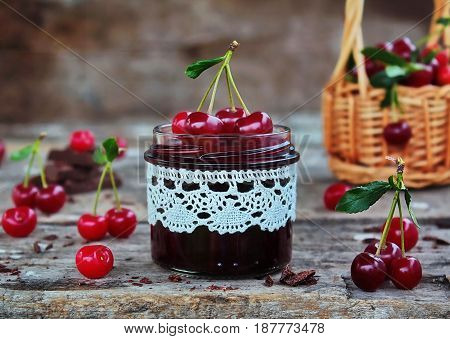 cherry jam with the chocolate in a glass jar and fresh cherries