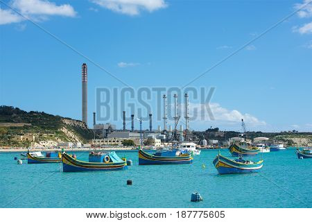 MARSAXLOKK, MALTA - May 1: native fishing boats in the ancient fishing village Marsaxlokk in Mediterranean sea on warm sunny day on Mayp 1, 2016. Panoramic view of Marsaxlokk village