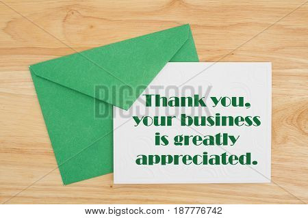 Thank You message An embossed white card with green envelope on wood with text Thank You your business is greatly appreciated