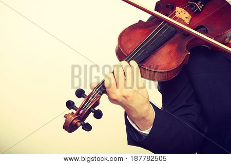 Music passion hobby concept. Close up of young man man dressed elegantly playing on wooden violin. Studio shot on white background