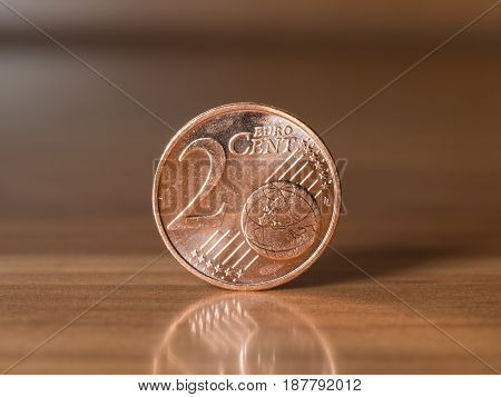 two euro cent standing on a wodden table with blurry background