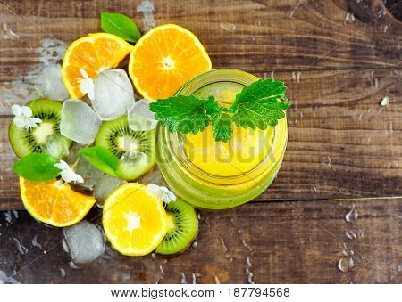 Citrus fruit and herbs water for detox or dieting in glass bottles on wooden board dark background selective focus square crop. Clean eating weight loss healthy lifestyle concept