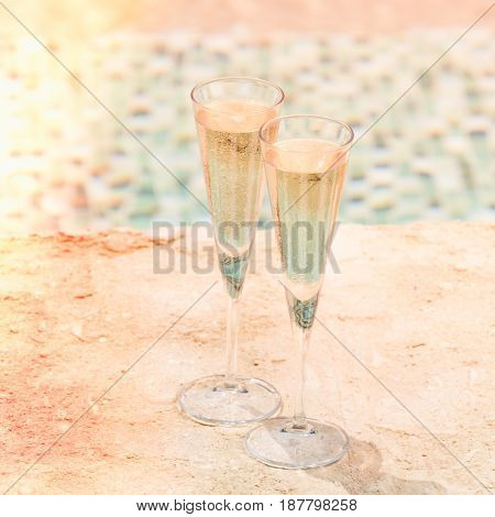 Two Glasses Of Prosecco   At The Edge Of A Resort Pool. Concept Of Luxury Vacation