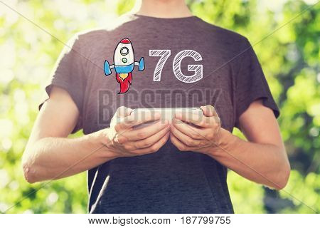 7G concept with young man holding his smartphone outside in the park toward sunset