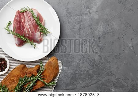 Raw duck breast, herbs and spices on gray stone background, copyspace