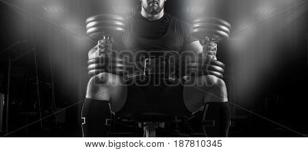 Professional Weightlifter Sits On A Bench With Two Dumbbells On His Lap
