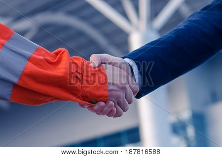businessman handshaking with worker. Handshake of suit and boilersuit. Business modern background